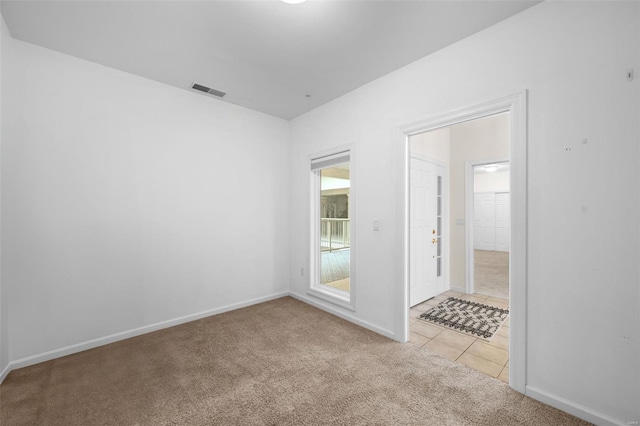 empty room with light colored carpet, baseboards, and light tile patterned floors