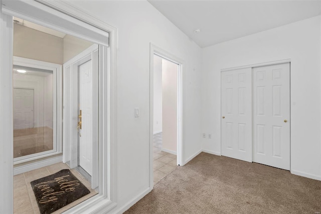 hall with light carpet and light tile patterned floors