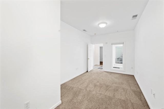 empty room featuring light colored carpet and baseboards