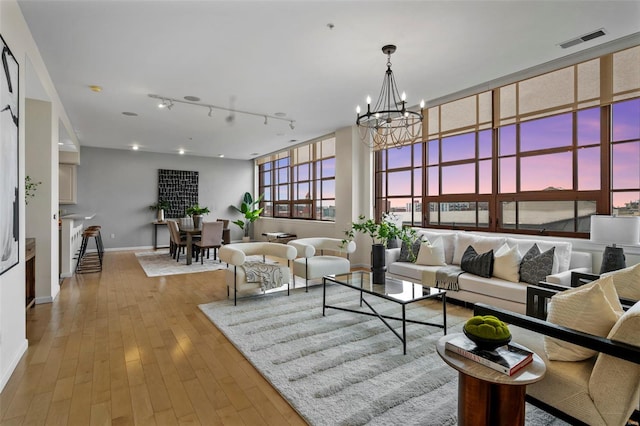 living room featuring a chandelier, baseboards, track lighting, and wood-type flooring