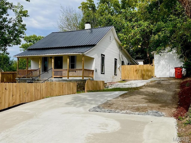 360 3rd St, Ellington, MO 63638 - view of front facade featuring a chimney, a porch, metal roof, fence, and a standing seam roof