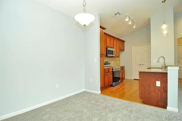 39 Kassebaum Ln Unit 303, Saint Louis, MO 63129 - kitchen featuring appliances with stainless steel finishes, a sink, vaulted ceiling, light colored carpet, and backsplash