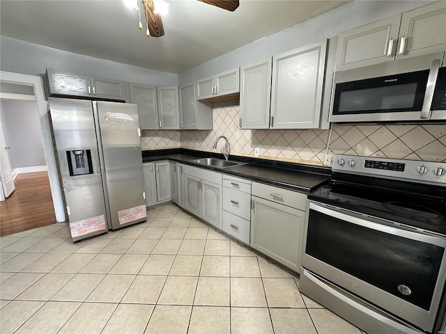 5056 Lindenwood Ave, Saint Louis, MO 63109 - kitchen featuring stainless steel appliances, a sink, dark countertops, light tile patterned floors, and tasteful backsplash