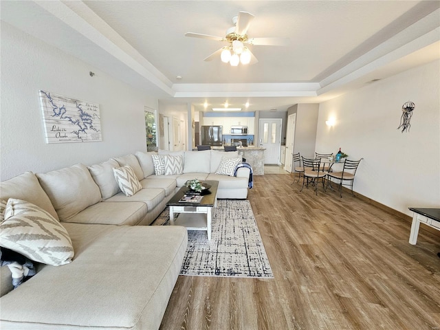 86 Aqua Fin Rd Unit 3B, Osage Beach, MO 65049 - living area featuring light wood-style flooring, a raised ceiling, a ceiling fan, and baseboards