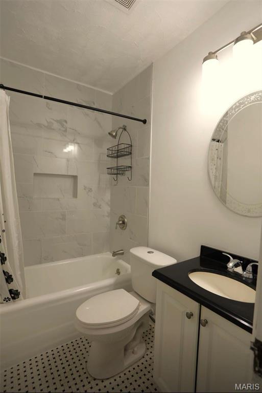7710 Saint Albans Ave, Maplewood, MO 63117 - bathroom featuring vanity, shower / bathtub combination with curtain, toilet, and tile patterned flooring