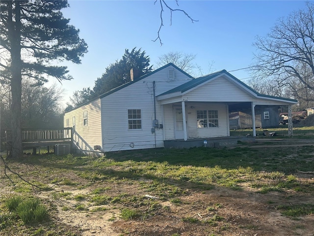 view of front facade featuring covered porch, a chimney, and central AC