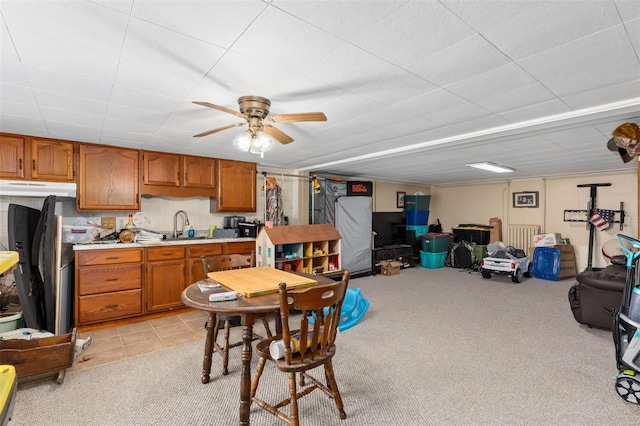 kitchen with light countertops, brown cabinets, light colored carpet, ceiling fan, and open floor plan
