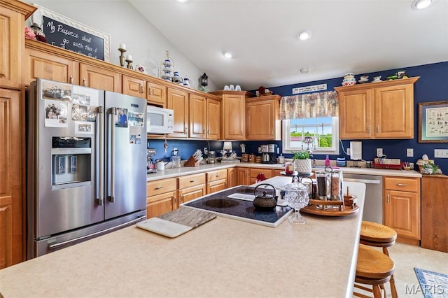 kitchen featuring stainless steel appliances, light countertops, a kitchen bar, recessed lighting, and lofted ceiling