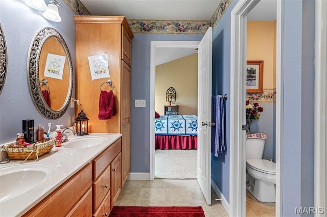 ensuite bathroom featuring tile patterned flooring, double vanity, baseboards, and toilet