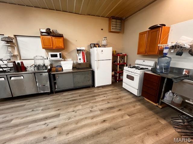 kitchen featuring white appliances, brown cabinetry, light wood finished floors, and wooden ceiling