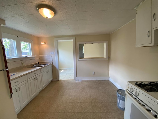 1309 Belton Ave, Webster Groves, MO 63119 - kitchen featuring a sink, white range with gas stovetop, light countertops, white cabinetry, and baseboards