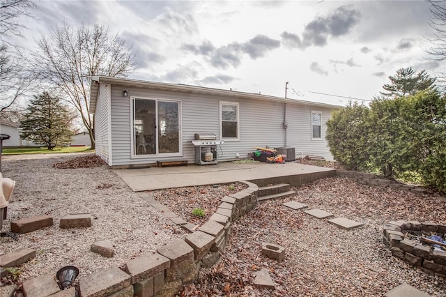 rear view of property featuring a patio area, cooling unit, and a fire pit