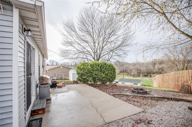 view of patio / terrace featuring fence, an outbuilding, a fire pit, and a shed