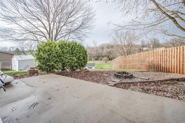 view of patio with a shed, an outdoor structure, a fire pit, and fence