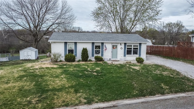 ranch-style home with brick siding, a shed, an outbuilding, and a shingled roof