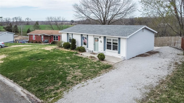 ranch-style house featuring brick siding, gravel driveway, and roof with shingles