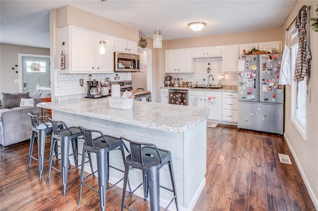 kitchen featuring stainless steel appliances, a sink, tasteful backsplash, and a kitchen breakfast bar