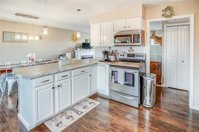 kitchen with appliances with stainless steel finishes, a peninsula, white cabinets, dark wood-style floors, and backsplash