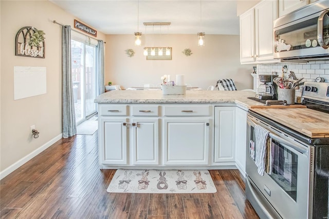 kitchen with appliances with stainless steel finishes, a peninsula, dark wood-type flooring, white cabinets, and tasteful backsplash