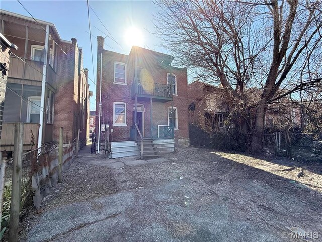 3949 Palm St, Saint Louis, MO 63107 - view of front of house with fence, brick siding, and a balcony
