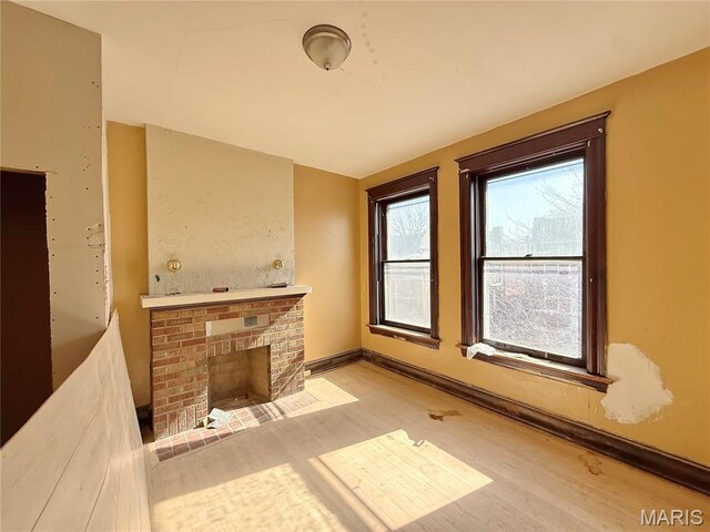 3949 Palm St, Saint Louis, MO 63107 - unfurnished living room with wood finished floors, a fireplace, and baseboards