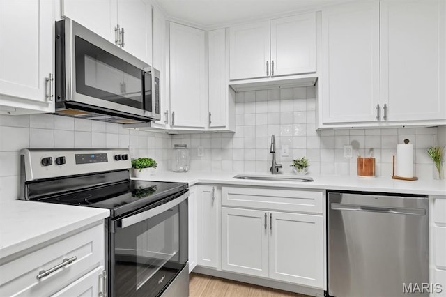 9003 Cardinal Ter, Saint Louis, MO 63144 - kitchen featuring appliances with stainless steel finishes, a sink, light countertops, and white cabinetry