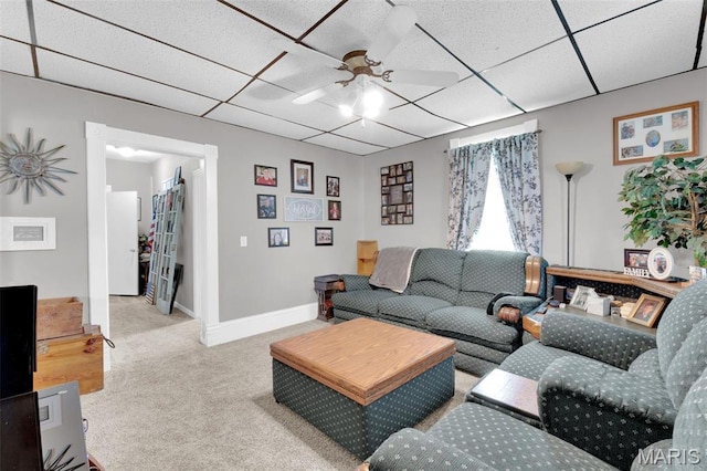 living area featuring carpet, ceiling fan, a drop ceiling, and baseboards