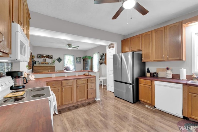 kitchen with white appliances, ceiling fan, light wood-style floors, and a peninsula