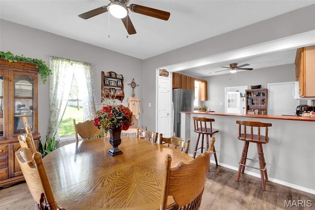dining room featuring a ceiling fan, light wood-style floors, and baseboards