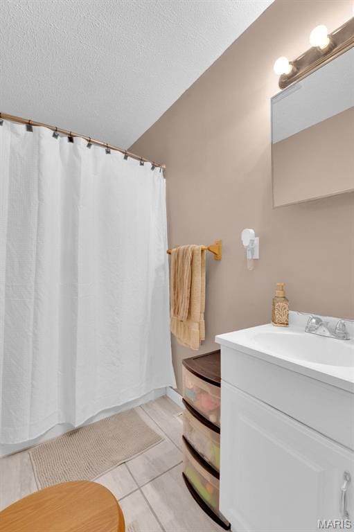 full bathroom with a textured ceiling, vanity, tile patterned flooring, and a shower with curtain