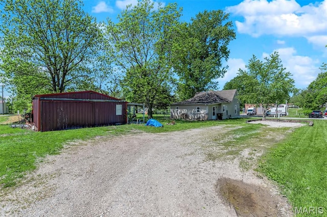 view of green lawn with an outbuilding and dirt driveway