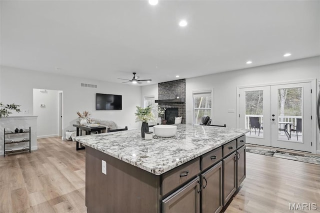 19011 Pinckney Manor Ct, Warrenton, MO 63383 - kitchen with a ceiling fan, a brick fireplace, light wood finished floors, recessed lighting, and a kitchen island