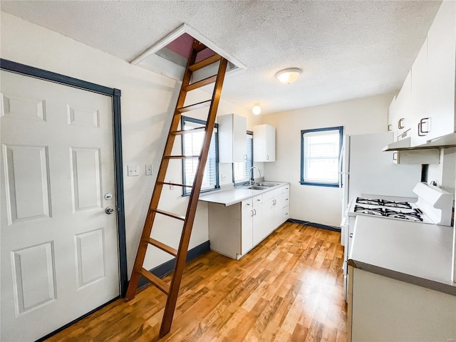 791 E Adams St, Nashville, IL 62263 - kitchen featuring a sink, a textured ceiling, white cabinetry, light wood-style floors, and baseboards