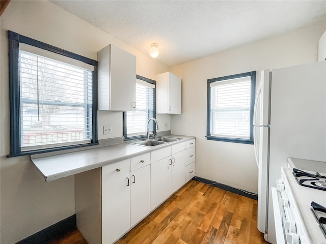 791 E Adams St, Nashville, IL 62263 - kitchen featuring a sink, white range with gas stovetop, light wood-type flooring, light countertops, and white cabinetry