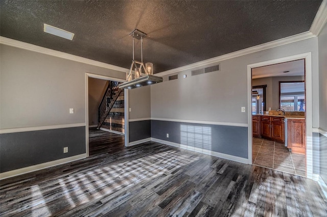 unfurnished dining area with dark wood-type flooring, stairway, ornamental molding, a textured ceiling, and baseboards