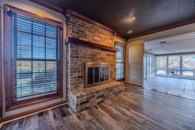 unfurnished living room featuring baseboards, a brick fireplace, wood finished floors, ornamental molding, and a textured ceiling