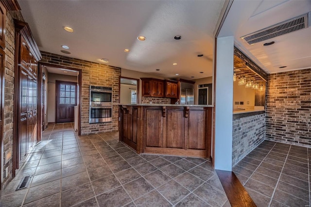 kitchen featuring double oven, brick wall, recessed lighting, a peninsula, and light countertops