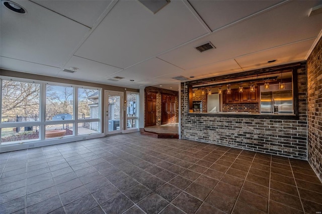 unfurnished living room featuring brick wall and dark tile patterned flooring