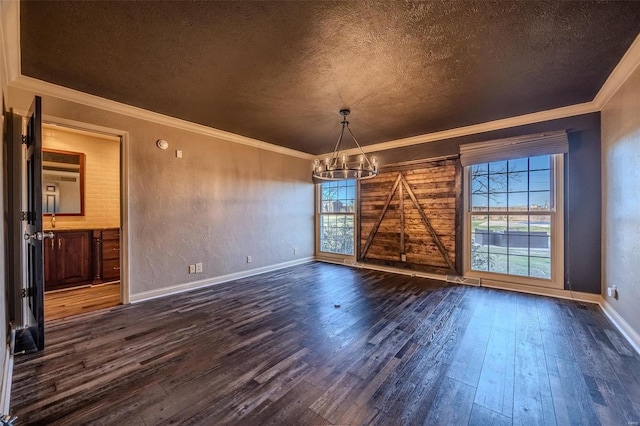 unfurnished dining area with a chandelier, dark wood finished floors, a textured ceiling, crown molding, and baseboards