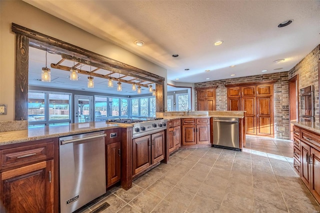 kitchen with stainless steel appliances, brick wall, light stone counters, brown cabinets, and recessed lighting