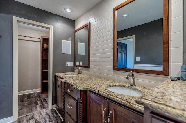 full bathroom with wood finished floors, decorative backsplash, double vanity, and baseboards