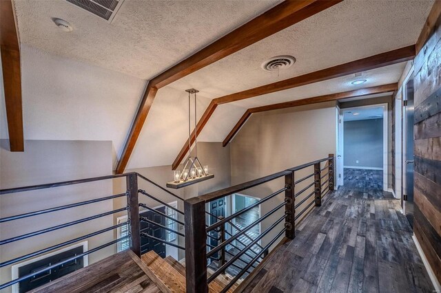staircase featuring a textured ceiling, wood finished floors, and a chandelier
