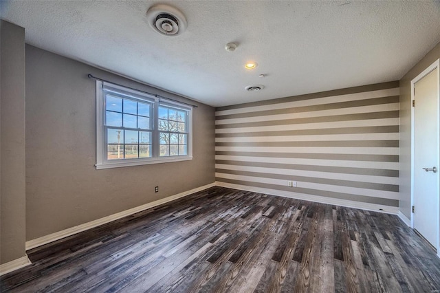 spare room with dark wood-style floors, a textured ceiling, and baseboards