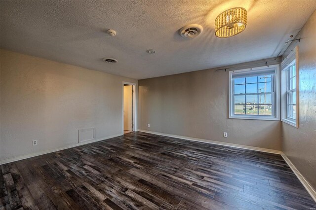 spare room featuring dark wood-style floors, a textured ceiling, baseboards, and a smoke detector