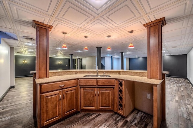 kitchen featuring ornate columns, a sink, dark wood-style flooring, and hanging light fixtures