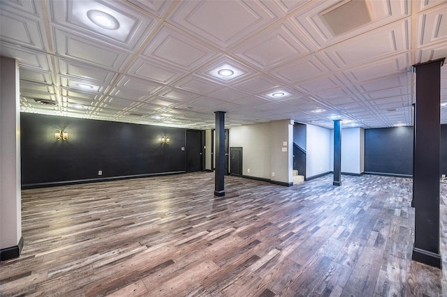 finished below grade area featuring wood finished floors, baseboards, and an ornate ceiling