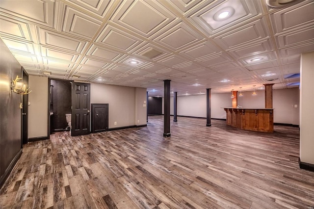 finished below grade area featuring baseboards, wood finished floors, an ornate ceiling, bar area, and recessed lighting