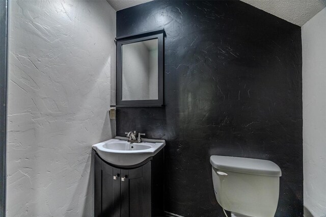 bathroom with toilet, a textured ceiling, and vanity