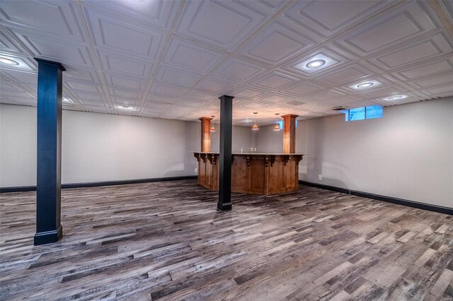 below grade area with dark wood finished floors, bar area, baseboards, an ornate ceiling, and recessed lighting