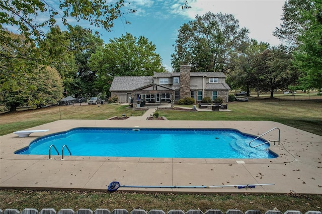 swimming pool featuring a patio, a lawn, and a diving board